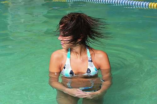 Model mit Cyberhair®-Perücke „Kelli“, das sich ihre Haare im Schwimbad ausschüttelt