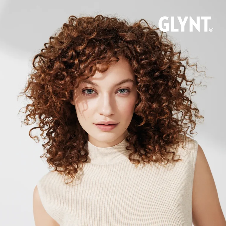 GLYNT®-Model „Carla“ mit lockigen, braunen Haaren, die frontal in die Kamera schaut