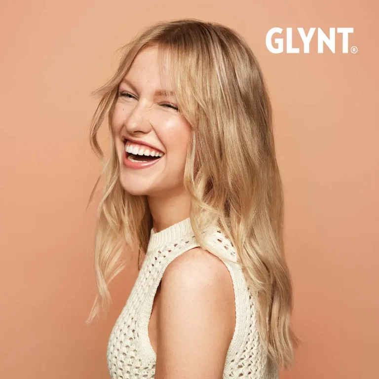 GLYNT®-Model „Libby“ mit blonden Haaren, die seitlich gedreht zur Kamera steht und in die Kamera lacht