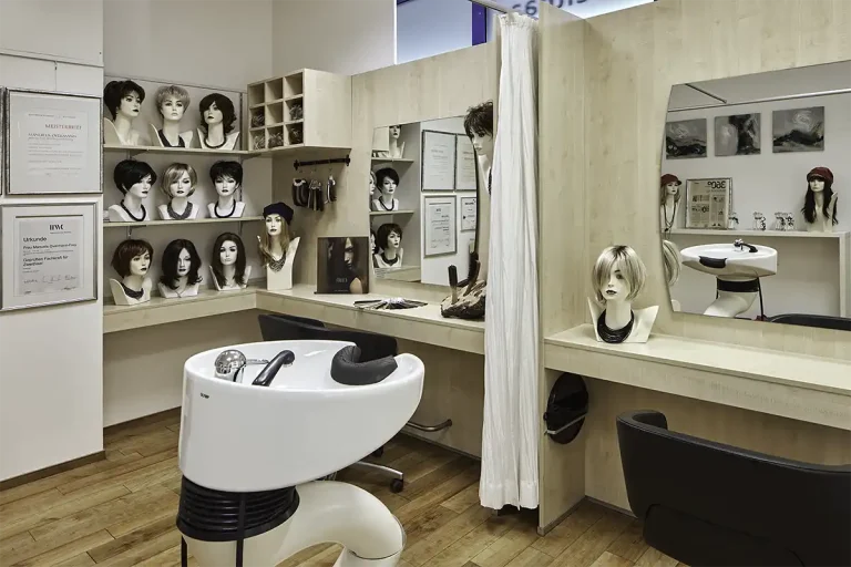 Blick im Zweithaarstudio auf einen Waschtisch mit Perücken im Hintergrund