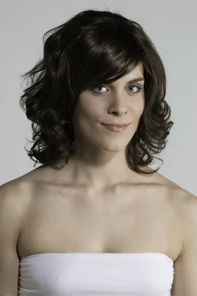 Model, das mit der Belle-Madame-Perücke „Chiara SF“ in Dark Mocca mit seitlich gedrehtem Kopf die Kamera blickt