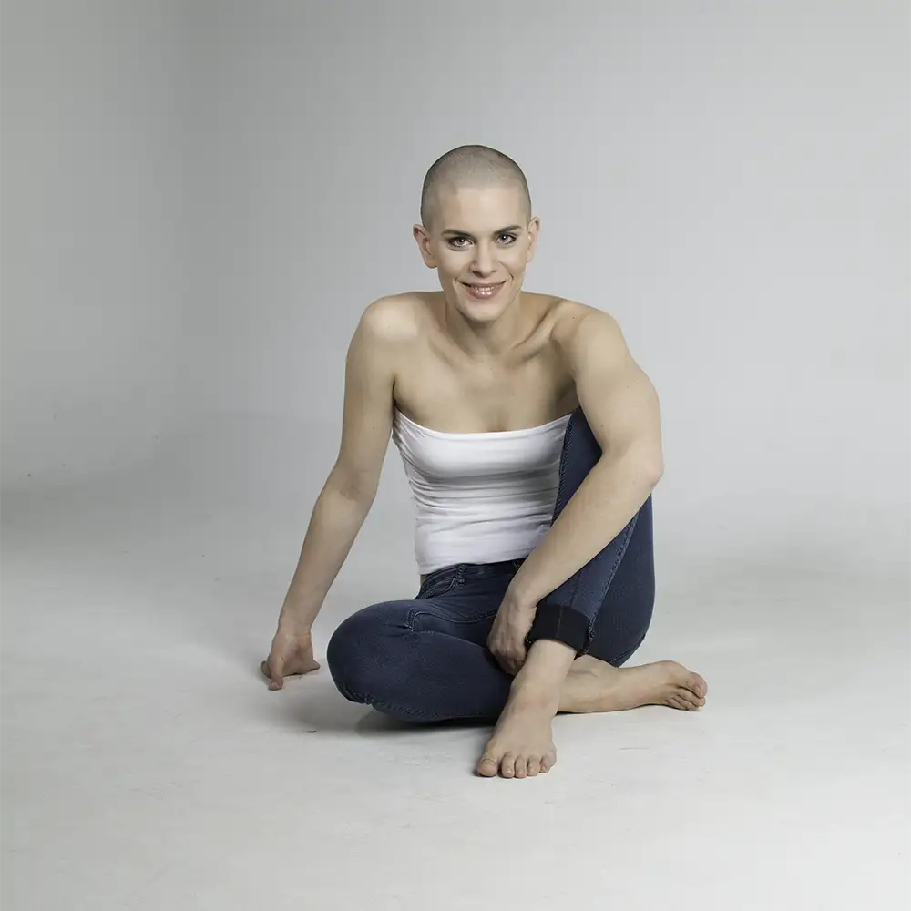 Model mit Glatze sitzt auf dem Boden und lächelt in die Kamera