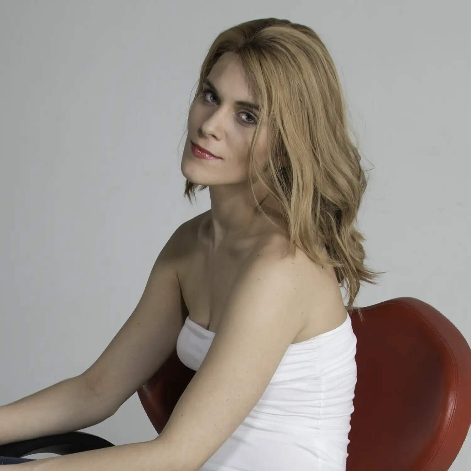 Frau, die mit Echthaarperücke mit dem Körper seitlich gedreht in die Kamera blickt