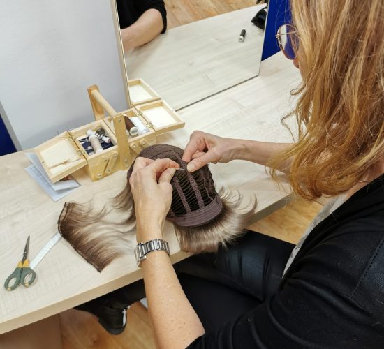 Friseurmeisterin passt eine Perücke im Zweithaarstudio an