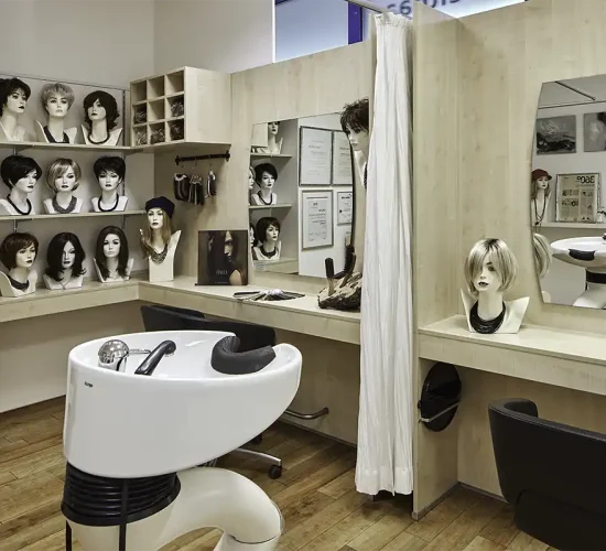 Blick im Zweithaarstudio auf einen Waschtisch mit Perücken im Hintergrund